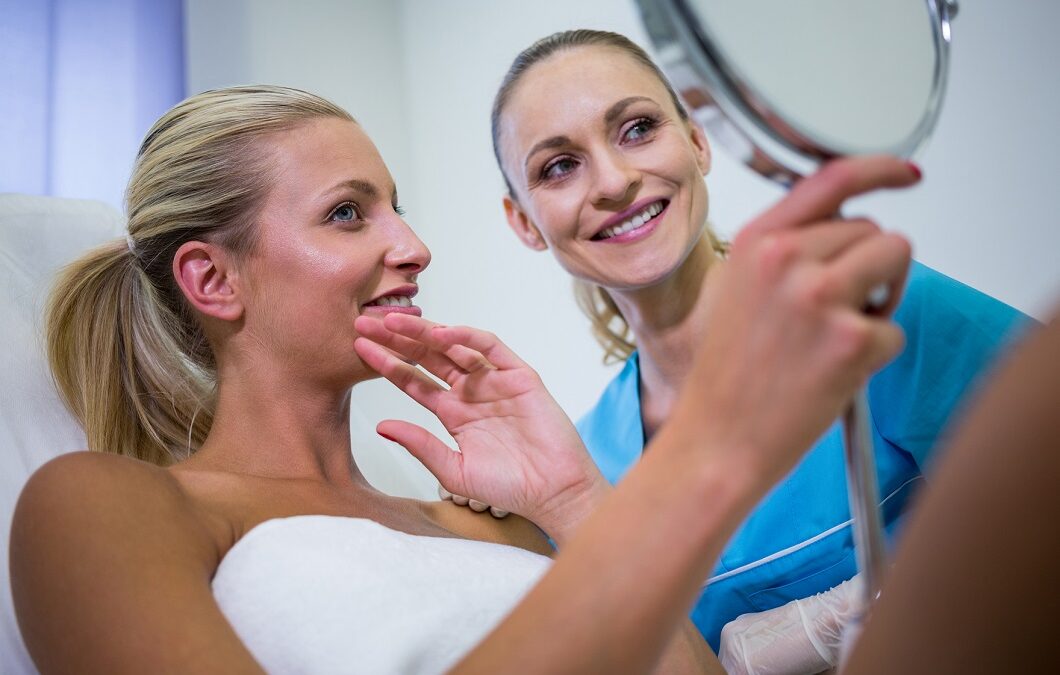 Happy woman checking her skin in the mirror after receiving cosmetic treatment